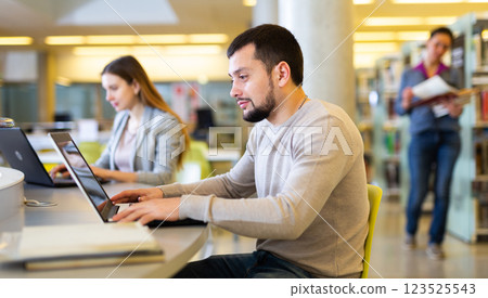 Young man working on science project in public library Young man working on science project in public library 123525543