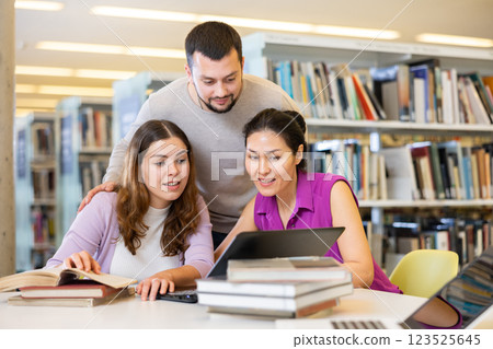 Group of students in the library is preparing for classes on a laptop Group of students in the library is preparing for classes on a laptop 123525645