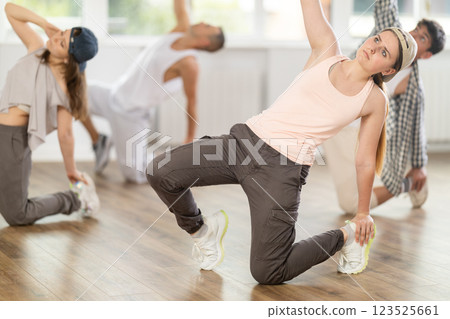 Girl and her students perform hip hop dance on one bent leg, movement in horizontal plane near floor 123525661
