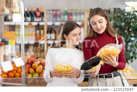 Teenage girl and her mother choosing chips in grocery store 123525697