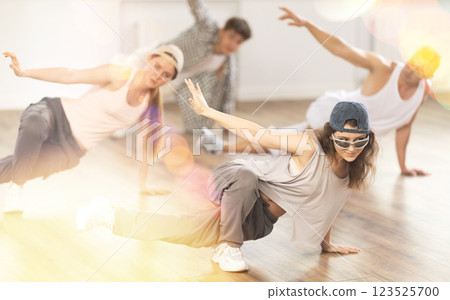 Girl and her students perform hip hop dance on one bent leg, movement in horizontal plane near floor 123525700