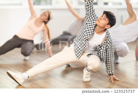 Young guy practicing breakdance floor-works in training hall Young guy practicing breakdance floor-works in training hall 123525737