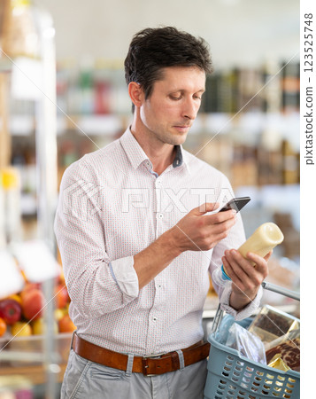 man scans a package of sauce on his phone 123525748