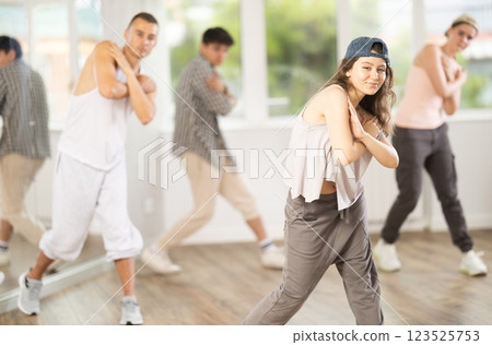 Young girl standing performs basic hip hop movements in front of group of students Young girl standing performs basic hip hop movements in front of group of students 123525753