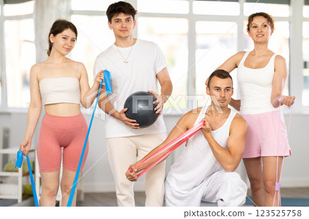 Positive sporty men and women wearing sportswear posing in fitness studio 123525758