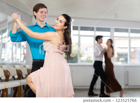 Couple in evening dresses enjoys pair dance tango, interacting with each other on floor 123525766
