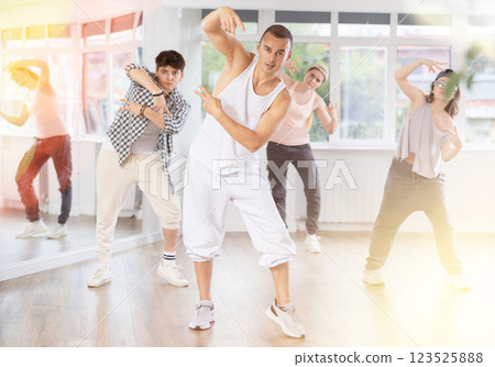 Young man standing performs basic hip hop movements in front of group of students Young man standing performs basic hip hop movements in front of group of students 123525888