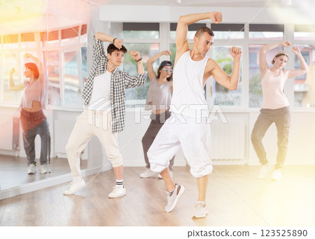Young man standing performs basic hip hop movements in front of group of students Young man standing performs basic hip hop movements in front of group of students 123525890