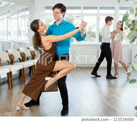 Couple in evening dresses enjoys pair dance tango, interacting with each other on floor Couple in evening dresses enjoys pair dance tango, interacting with each other on floor 123526000