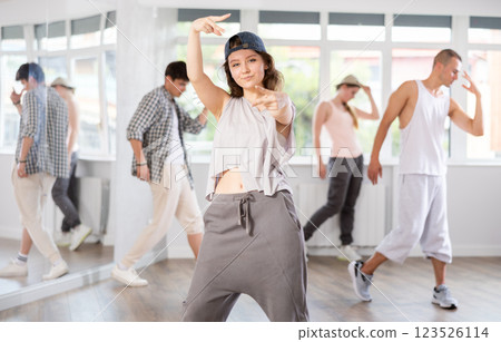 Young girl breakdancing against background of group members Young girl breakdancing against background of group members 123526114