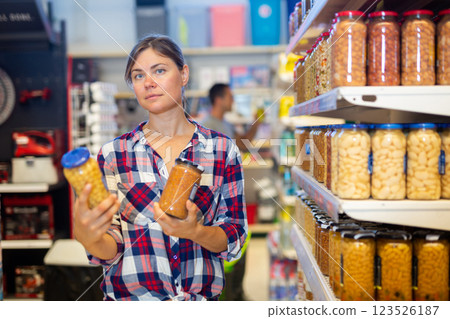 Positive female customer holding glass jar of beans in supermarket Positive female customer holding glass jar of beans in supermarket 123526187