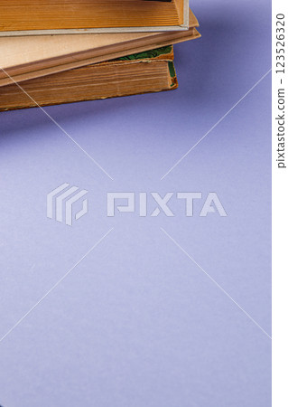 Stacked antique books resting on a purple surface with soft lighting Stacked antique books resting on a purple surface with soft lighting 123526320