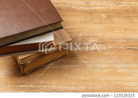 Stacked vintage books on a wooden table with natural lighting 123526325