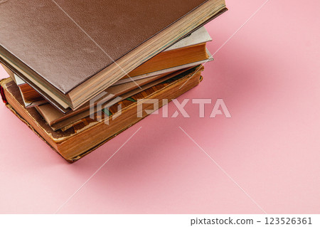 Stacked books in various colors resting on a pink surface 123526361