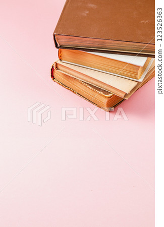 Stacked vintage books on a pink background showcasing classic literature Stacked vintage books on a pink background showcasing classic literature 123526363