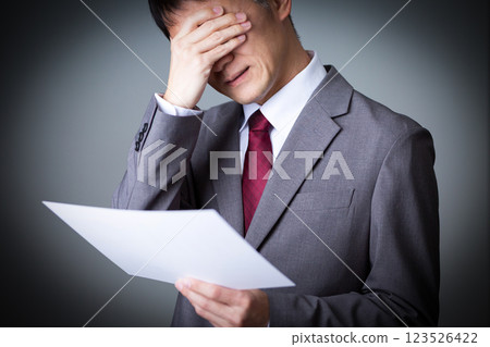 A middle-aged male businessman looking at documents and worrying 123526422