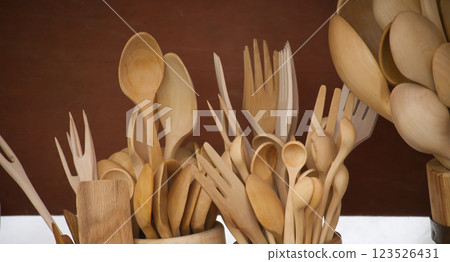 Rustic wooden kitchen utensils, including spoons and forks, displayed with a warm, handcrafted feel. 123526431
