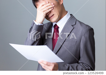 一位中年男性商人看著文件，憂心忡忡 123526499