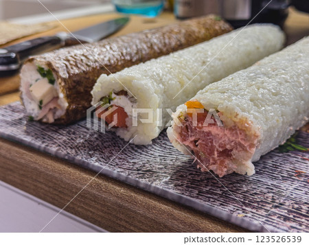 Sushi rolls prepared on a wooden kitchen counter in a cozy home setting Sushi rolls prepared on a wooden kitchen counter in a cozy home setting 123526539