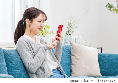 A woman operating a smartphone on the sofa. A woman operating a smartphone on the sofa. 123527356