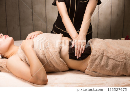 A young Asian woman has her tummy wiped with a towel. A young Asian woman has her tummy wiped with a towel. 123527675