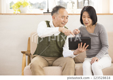 Elderly couple having a conversation while looking at a tablet in the living room 123528618