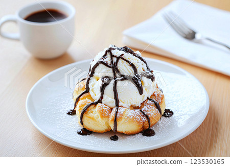 Gourmet profiteroles with chocolate drizzle and vanilla bean ice cream, showcasing classic French 123530165