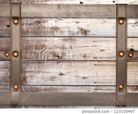 An old trunk lid with leather straps with rivets. Horizontal background with strips of leather trim on wooden planks. Retro backdrop with vintage wooden chests upholstered in leather with brass snaps An old trunk lid with leather straps with rivets. Horizontal background with strips of leather trim on wooden planks. Retro backdrop with vintage wooden chests upholstered in leather with brass snaps 123530497