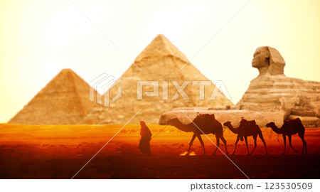 Caravan of camels, Great Sphinx and Pyramids of Chephren and Cheops, Cairo, Egypt. Man with dromedary, statue of Sphinx and two pyramids, Giza complex (Giza Necropolis). On sunrise sky background Caravan of camels, Great Sphinx and Pyramids of Chephren and Cheops, Cairo, Egypt. Man with dromedary, statue of Sphinx and two pyramids, Giza complex (Giza Necropolis). On sunrise sky background 123530509