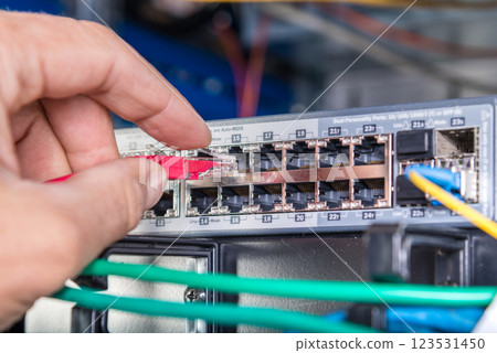 hand of engineer plugging in ethernet cable into server switch p 123531450