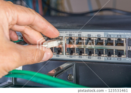 hand of engineer plugging in ethernet cable into server switch p 123531461