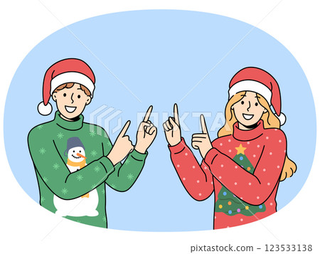 Man and woman in christmas sweaters point fingers upward to visit new year sale. 123533138