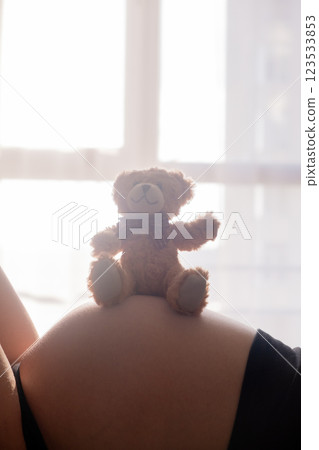 Pregnant Woman with toy Bear on Belly Pregnant Woman with toy Bear on Belly 123533853