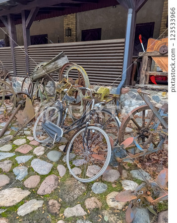 Vintage Bicycles and Rusty Wheels Scattered on Cobblestone Yard, Rustic Outdoor . High quality photo 123533966