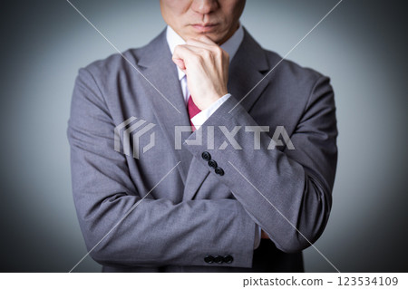 A middle-aged male businessman wearing a gray suit and worried A middle-aged male businessman wearing a gray suit and worried 123534109