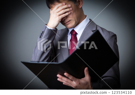 A middle-aged male businessman wearing a gray suit and worried 123534110