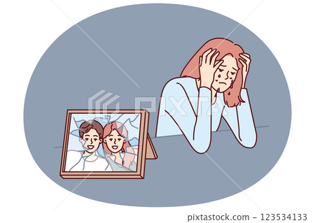 Woman cries after breaking up with husband and is sad sitting near broken photo with happy family Woman cries after breaking up with husband and is sad sitting near broken photo with happy family 123534133