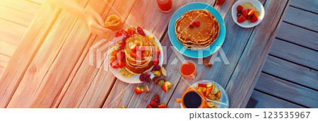 Family enjoys a delightful breakfast with pancakes and fruit on a sunny morning at the table 123535967