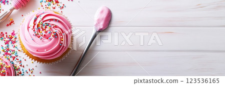 Overhead view of a vibrant cupcake decorating setup with icing sprinkles and tools 123536165