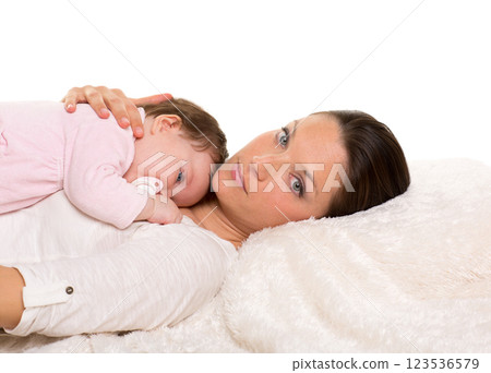 Baby girl and mother lying happy together on white fur 123536579