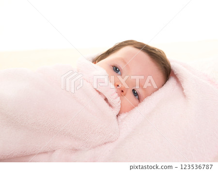 baby girl under hidden pink blanket on white fur 123536787