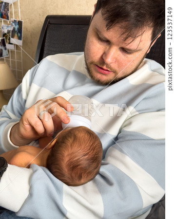 Tender Moment: Man Feeding Baby on Bed 123537149