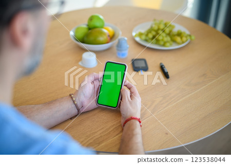 Man is checking blood glucose level using smartphone app. 123538044