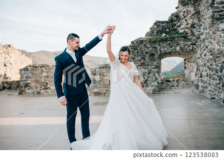 Bride and groom dancing, looking at each other. Wedding couple standing outside near ruins. Bride and groom dancing, looking at each other. Wedding couple standing outside near ruins. 123538083