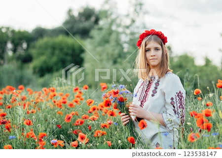 Ukraine's Constitution day. 24 August. Patriotic holiday. outdoor portrait. Girl in traditional embroidery collecting poppies in field. Blooming Poppies memory symbol. 123538147