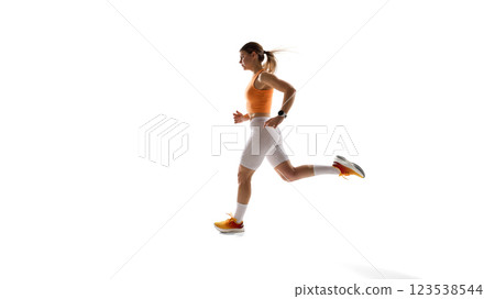 Young sportive woman in orange top and white leggings in motion, running against white studio background. Training 123538544