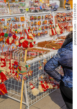 Handmade Martenitsa decorations hanging on display at an outdoor market. Traditional Bulgarian red and white ornaments symbolize health, prosperity Handmade Martenitsa decorations hanging on display at an outdoor market. Traditional Bulgarian red and white ornaments symbolize health, prosperity 123538550
