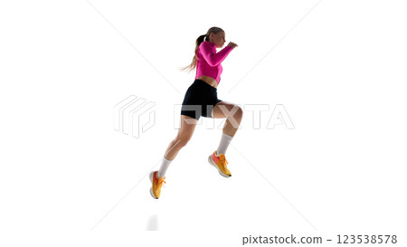 Intense female runner mid-leap, demonstrating speed, control, and determination in professional training against white studio background. 123538578