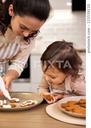 happy mother and little child girl bake cookies on the kitchen at home 123539210