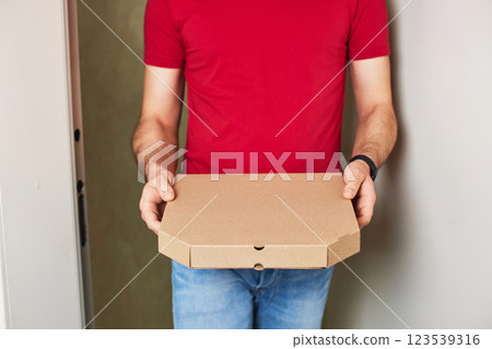 delivery man giving food order and holding pizza box standing at doorway delivery man giving food order and holding pizza box standing at doorway 123539316